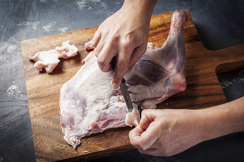 Bring the leg back to the cutting board and trim clean of the skin.