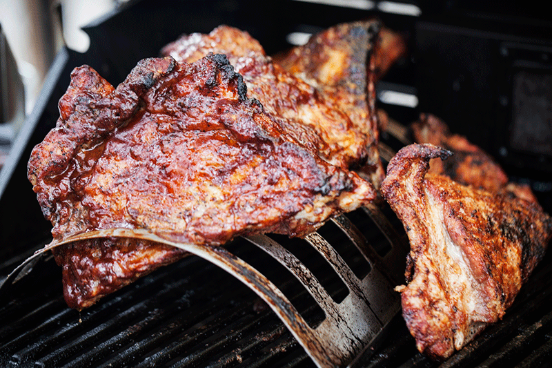 After basting the ribs for the first time, lean the rubbed ribs on the rack to allow them to continue cooking in the same temperature zone as the once in the rack. The reason that I have used the rib rack is that sauces and glazes are high in sugar content. Using a rack ensures that the sauce and glaze stay on the ribs as opposed to losing half of it to the grill. It's also very important to note that because of the high sugar content, they burn fast. This is why they are only applied closer to the end of the cooking time. 