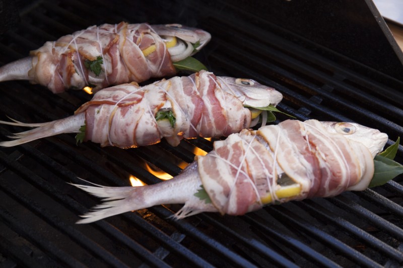 Beginning with the fish, over direct heat, grill them on either side for about 7 minutes or until the bacon crisps.